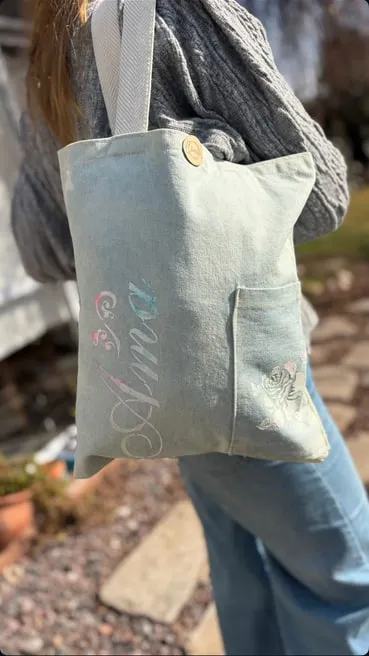 Tote bag chica verde agua con la palabra "Ama" pintada y un bolsillo